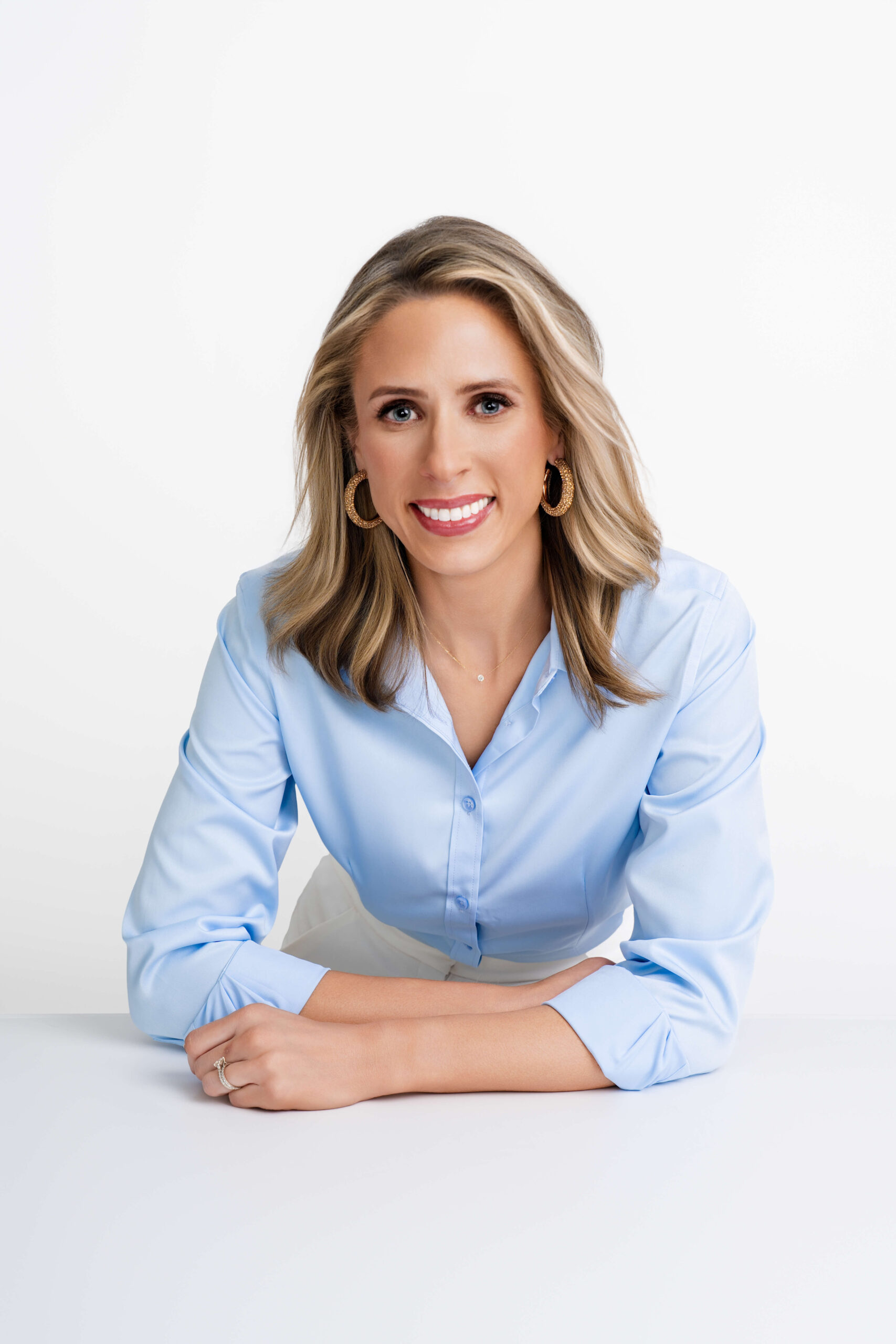 Professional branding portrait of a confident businesswoman in a light blue blouse and white slacks, styled with bold pink heels. Captured by Breanne Fine Portraiture in Birmingham, Alabama.