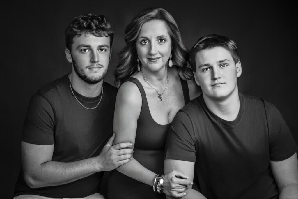Studio family portrait of mother with two sons in black outfits against dark background made by Breanne Cook of Breanne Fine Portraiture in Birmingham Alabama