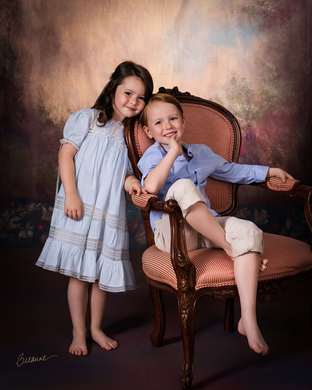 Brother and sister with freckles cuddling in an antique armchair during a sibling portrait session near Mountain Brook, Alabama